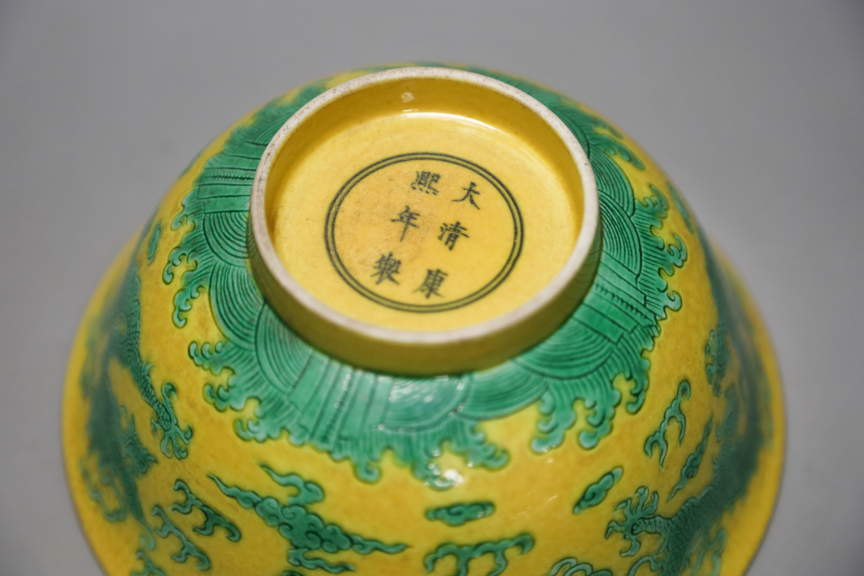 A Chinese yellow ground sgraffito’dragon’ bowl, Kangxi mark but later 15cm diameter